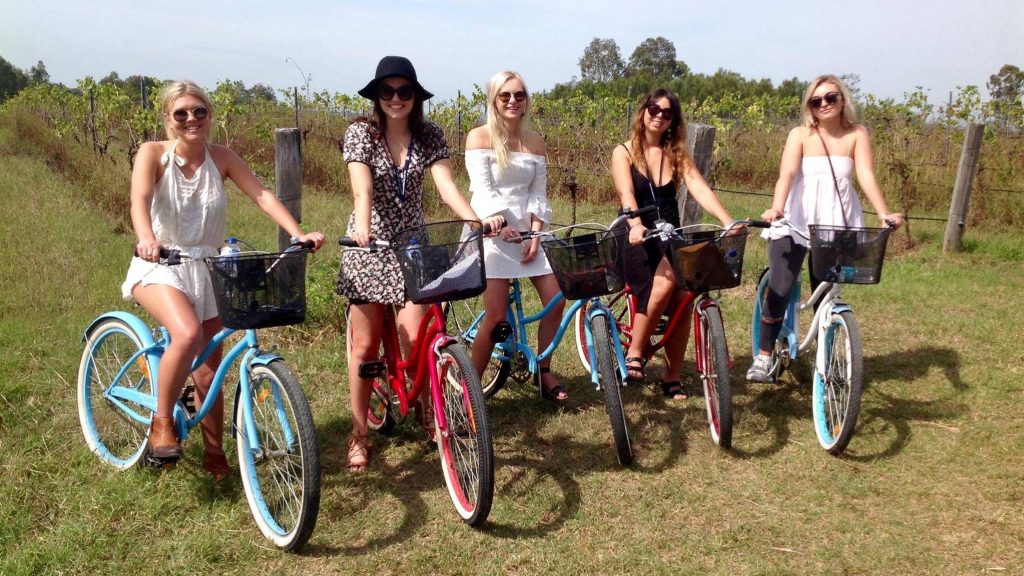 girls riding bicycles though the vineyards